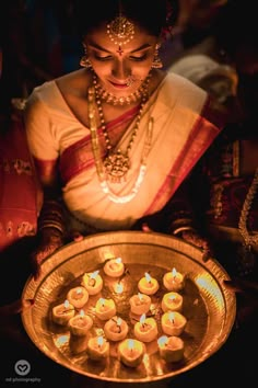 a woman holding a tray filled with lit candles