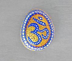 an egg painted with blue, yellow and white designs on a gray background is shown