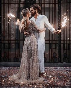 a man and woman are holding sparklers in their hands while standing next to each other