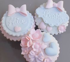 three cupcakes decorated with pink and blue icing on top of a table