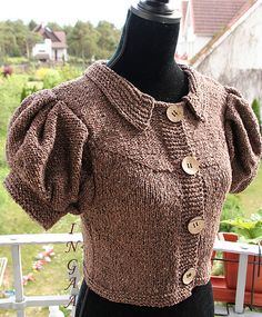 a knitted sweater with buttons on the shoulders