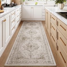 a kitchen with white cabinets and beige rugs on the floor in front of windows