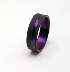 a purple and black ring sitting on top of a white table