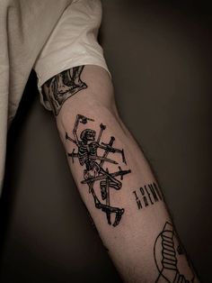 a man's arm with a skeleton and cross tattoo on the left side of his arm