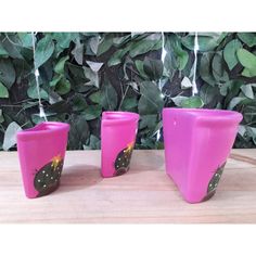 three pink vases sitting on top of a wooden table