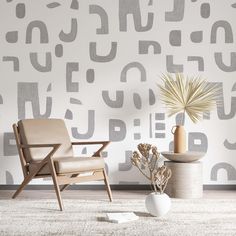 two chairs and a vase in front of a wall with geometric designs on the walls