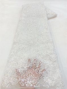 a white dress laying on top of a bed covered in sequins and pearls