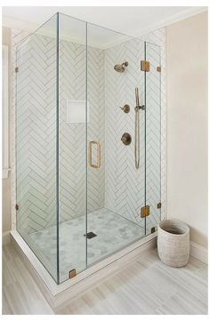 a walk in shower sitting next to a white wall and wooden floor with gold accents