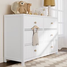 a teddy bear sitting on top of a white dresser