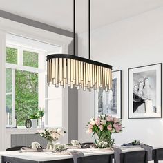 a dining room table and chairs with flowers in vases on the table next to it