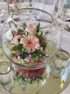 a vase filled with flowers sitting on top of a table next to wine glasses and candles