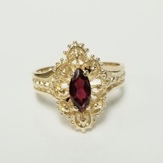 a gold ring with a red stone in the center and filigrees around it