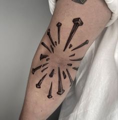 a man with a tattoo on his arm has an arrow and some nails in it