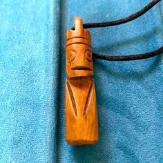 a wooden necklace with a carved face on it's end and a cord attached to it