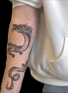 a woman's arm with a dragon tattoo on the left side of her arm