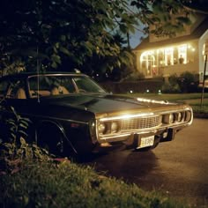 an old car is parked on the side of the road in front of a house