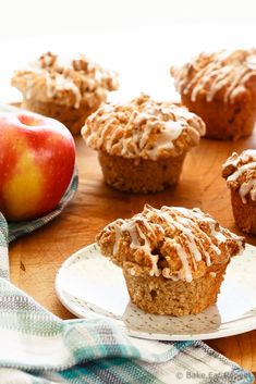 three muffins on a cutting board with an apple