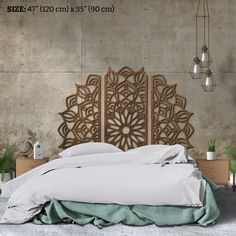 a bed with an intricate headboard made out of wood and white linens, sitting in front of a concrete wall