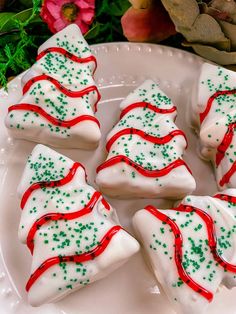 christmas tree shaped cookies on a plate with green and red sprinkles