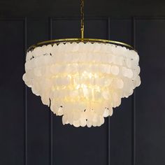 a chandelier hanging from the ceiling in a room with black walls and wooden flooring