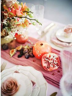 the table is set with flowers and fruit