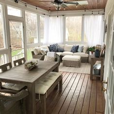 a screened porch with white furniture and wood flooring