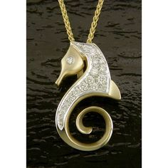 a gold and diamond seahorse pendant on a black surface