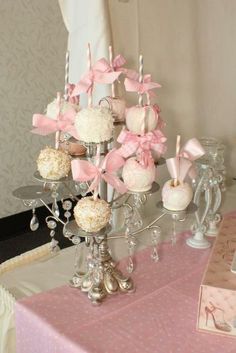 a table topped with lots of cupcakes and candy covered in pink bows on top of it