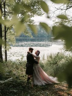 a bride and groom embracing in front of the water