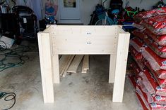 a table made out of plywood and bags of wood sitting on the floor in a garage