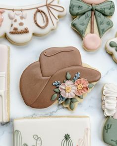 some decorated cookies are laying on a white counter top and one has a cowboy hat, the other is cactus