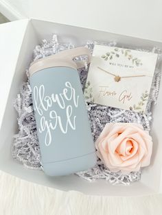 a gift box containing a flower girl water bottle, necklace and note card in it