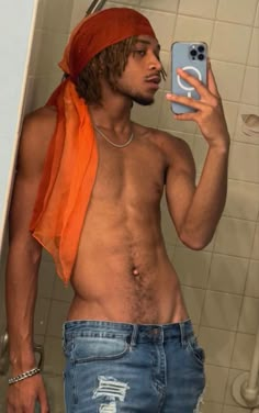 a shirtless man takes a selfie in the bathroom mirror with his cell phone