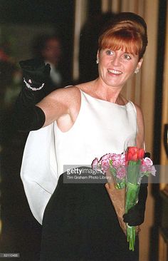 a woman in a white dress and black gloves is holding a bouquet with red flowers