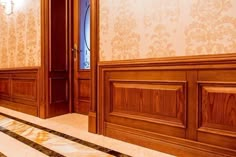 an empty room with wood paneling and marble flooring on the ground, in front of two large wooden doors