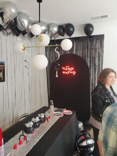 a woman standing in front of a table filled with cakes and cupcakes at a party