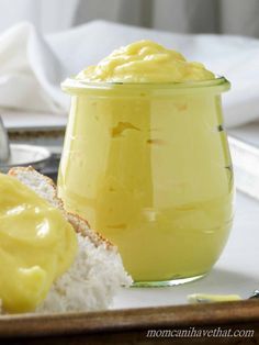 a glass jar filled with yellow liquid next to bread