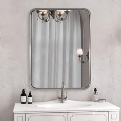 a bathroom vanity with a large mirror above it and two bottles on the counter next to it