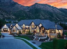 a large house with lots of windows and lights on it's front yard in the mountains