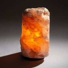 an orange rock sitting on top of a white table next to a black background with the light shining through it