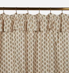 the curtain is hanging on a rod and it has a flower pattern in beige colors