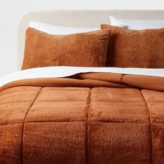 an orange comforter and pillows on a bed