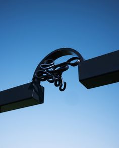 a metal sculpture with scissors hanging from it's sides in the air against a blue sky