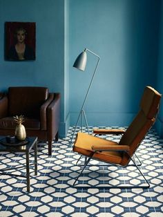 a living room with blue walls and white tile on the floor, two brown leather chairs