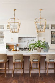 a kitchen with white cabinets and wooden flooring, two hanging lights above the island