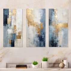 two paintings on a wall in a living room with white and gold accents, one blue and the other beige