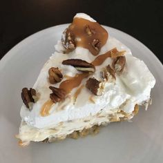 a piece of pie on a white plate with pecans and caramel toppings