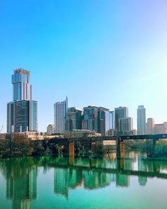 the city skyline is reflected in the still water of the river that runs through it