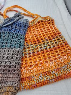 three crocheted purses sitting on top of a white bed next to each other