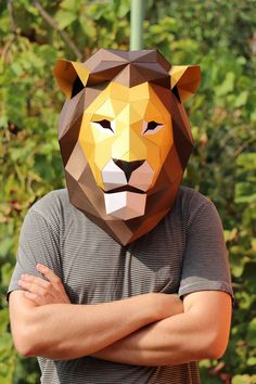 a man standing with his arms crossed in front of a paper mask of a lion